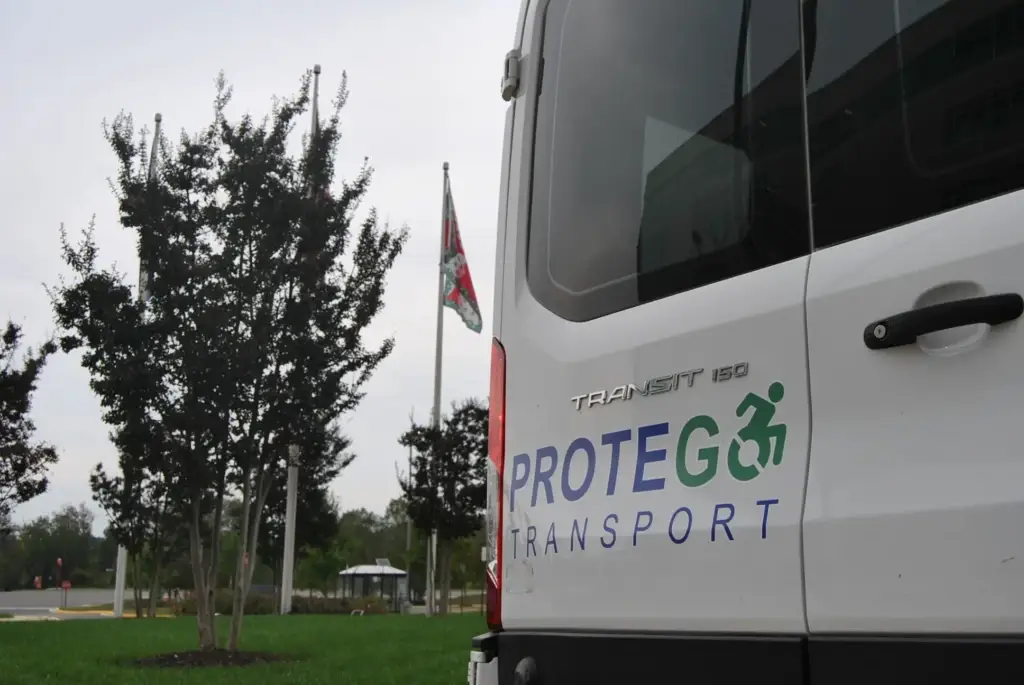 Protego Transport wheelchair-accessible medical transportation van parked beside U.S. and Virginia flags in Northern Virginia